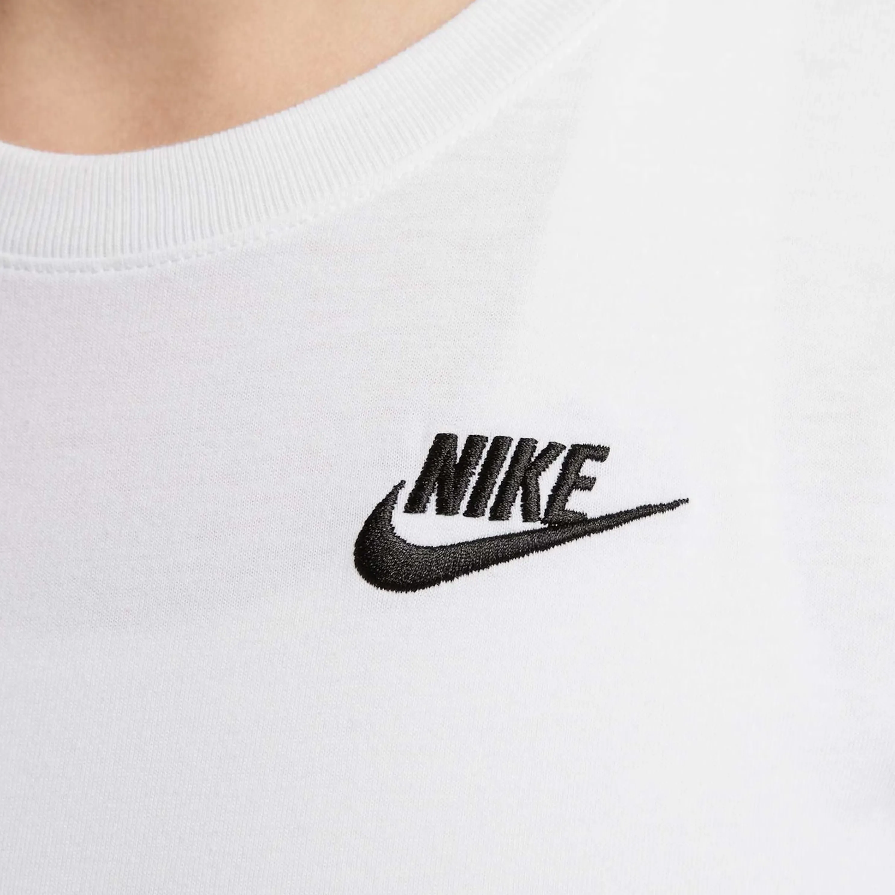 Detalhe do logo Nike bordado em preto na blusa branca feminina.